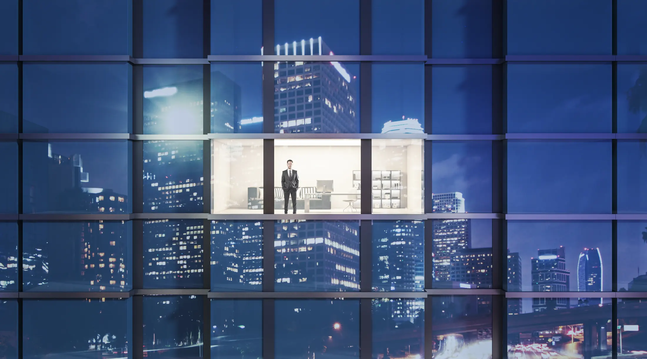 Security leader standing in a lit office overlooking the city at night